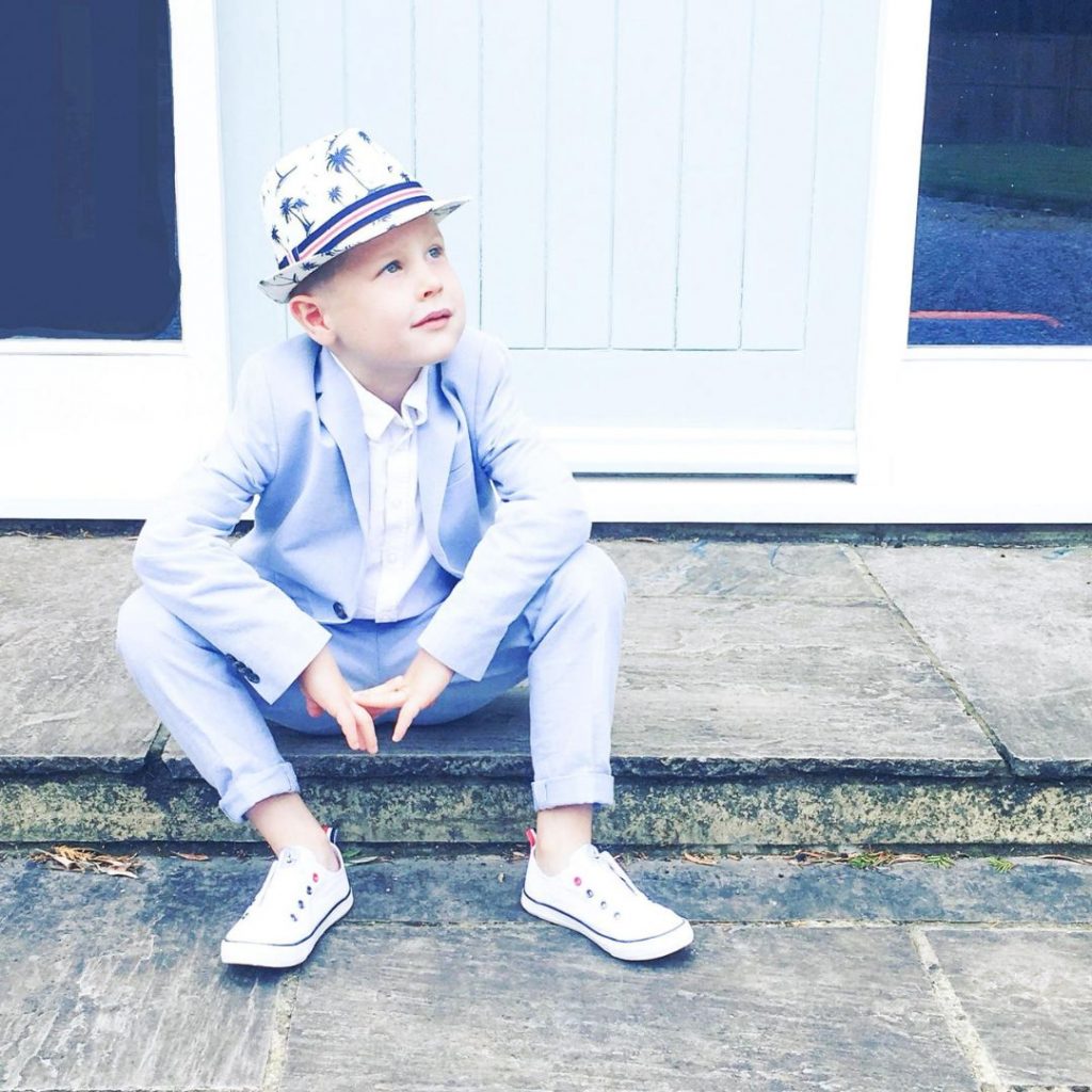 Image of a young boy sat on a front step, wearing a light blue suit and a trilby hat - How Felicity Finds